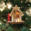 A wooden Christmas tree ornament shaped like a doghouse with a Boxer sign and a carved Boxer dog inside, hanging on a tree with lights. A small red fire hydrant decoration is attached to the side.
