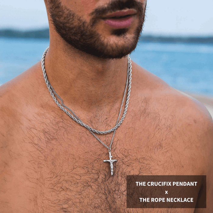 Close-up of a male model wearing the Build Your Own Bundle - Silver, featuring a silver crucifix pendant paired with a twisted silver rope necklace, both bold men's jewelry pieces.