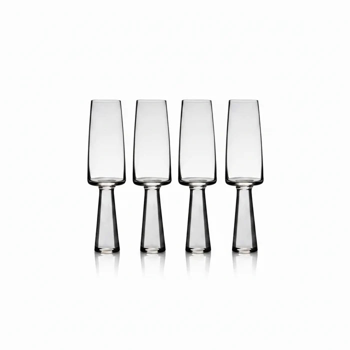 Set of four clear glass flutes on a white background