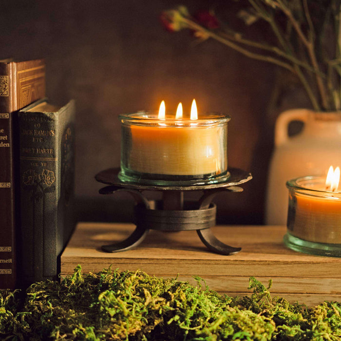 3-wick pure beeswax candle burning on forged pedestal holder