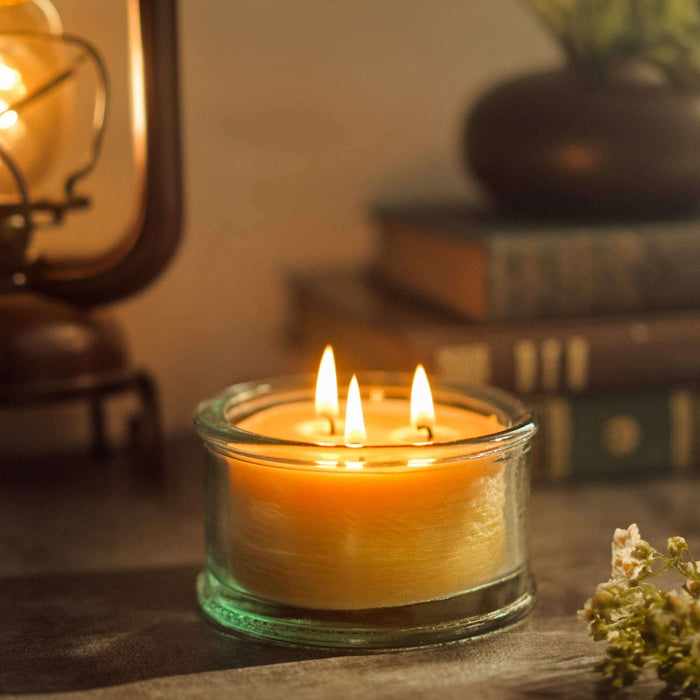 3-wick pure beeswax candle burning on table top