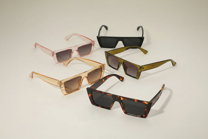 Five pairs of sunglasses in different colors on a light gray background
