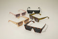 Five pairs of sunglasses in different colors on a light gray background