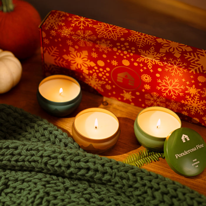 Scented Candle Gift Set featuring three 8oz candles in decorative tins on a wooden table with winter decor. perfect candles for xmas