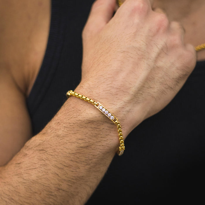 Close-up of a male wrist wearing The Atlas Ice Bracelet, a gold-tone men's jewelry piece featuring a sleek band with sparkling cubic zirconia accents, bold by design.