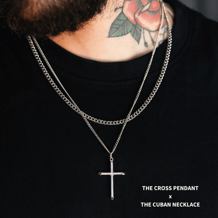 Close-up of a male model wearing The Cross Essentials Bundle - Silver, featuring a bold silver cross pendant and a matching Cuban chain necklace, styled with a black shirt.