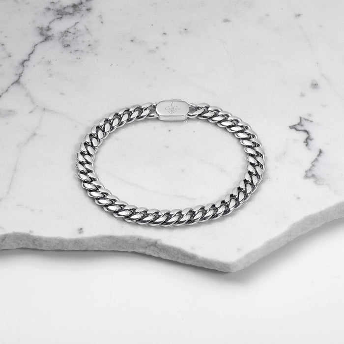 The Cuban Bracelet - Silver displayed on a marble surface, featuring a bold, polished silver chain link design with a secure clasp, embodying luxury jewelry crafted to be noticed. Bold by Design.