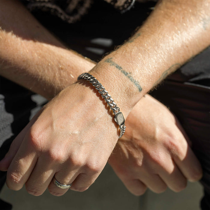 A close-up lifestyle shot of a person wearing The Cuban Bracelet - Silver, featuring a bold, polished silver chain design with a sleek clasp, showcasing men's jewelry with confidence.
