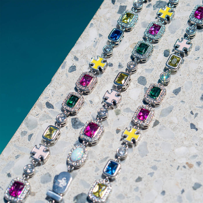 Close-up of multiple colorful gemstone and cubic zirconia bracelets for men arranged on a textured stone surface, showcasing bold, luxury design details of The Gemstone Bracelet.