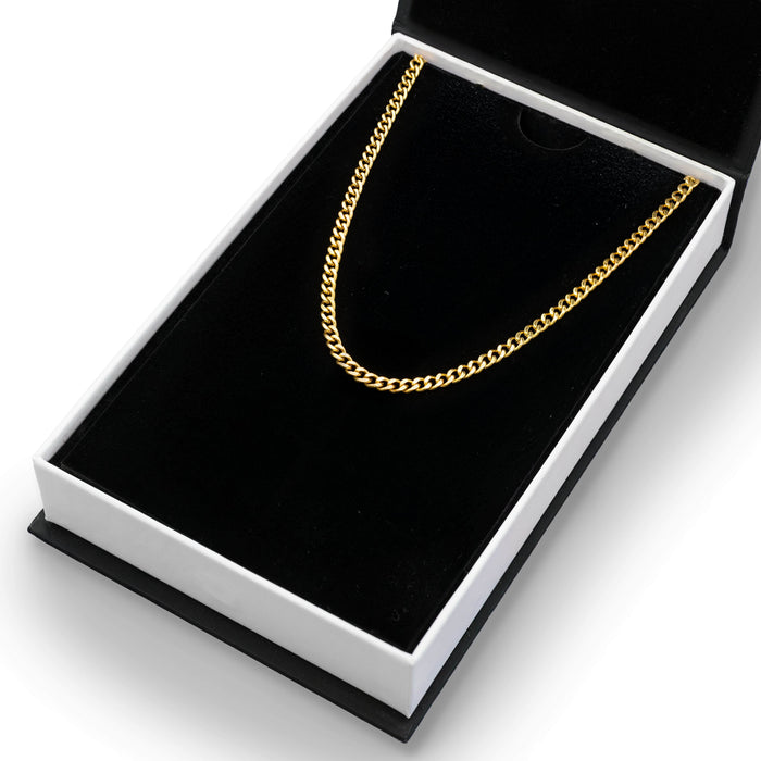 The Gold Cuban Necklace - Essentials Collection displayed in a black velvet-lined box, showcasing a bold men's gold Cuban link chain designed for standout luxury jewelry.