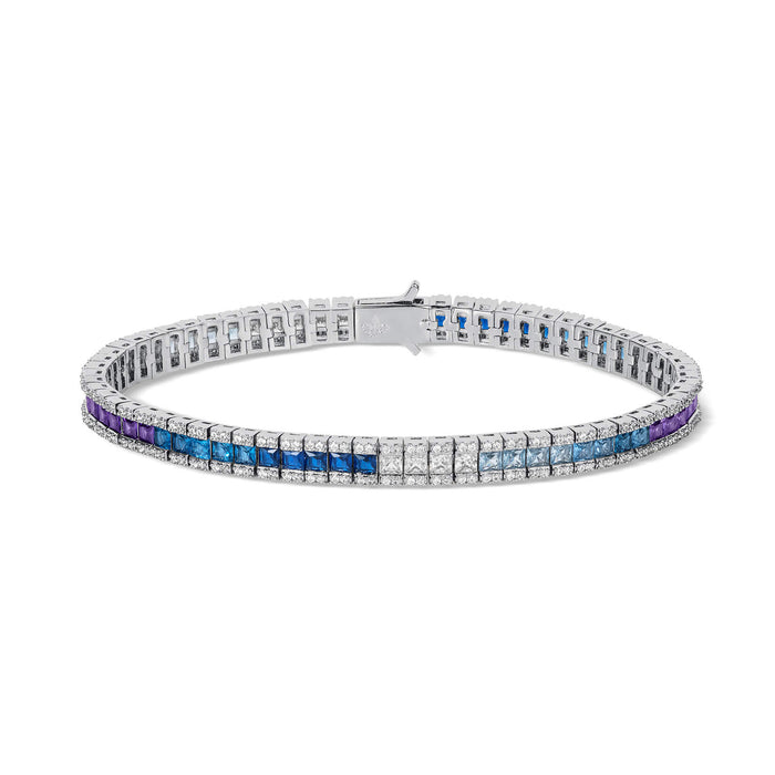 The Iced Atlantis Bracelet is a men's luxury jewelry piece featuring a sleek silver-tone metal band with a row of alternating blue, purple, and clear cubic zirconia stones, designed to be noticed.