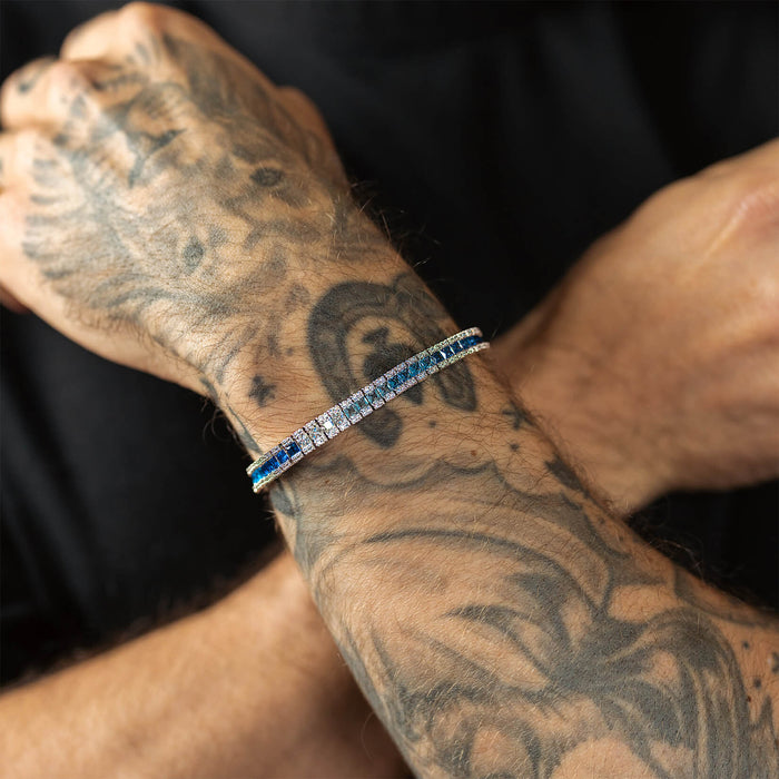 The Iced Atlantis Bracelet on a tattooed male wrist featuring a sleek design with blue and clear cubic zirconia stones, reflecting bold luxury jewelry by Ralph Christian, bold by design.
