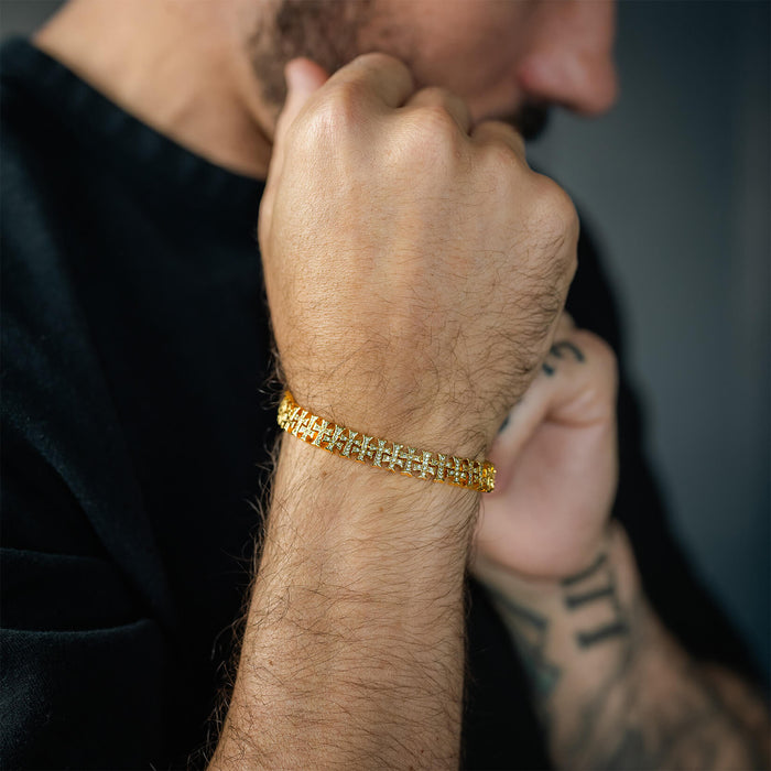 Man wearing The Iced Creed Bracelet - Gold, a bold men's jewelry piece featuring a gold-tone finish with an intricate design, styled with a black shirt in a lifestyle shot.