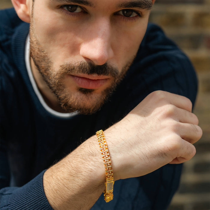 Man wearing The Iced Creed Bracelet - Gold, a bold men's jewelry piece with a gold-tone finish and intricate link design, photographed in natural light with a casual outfit.