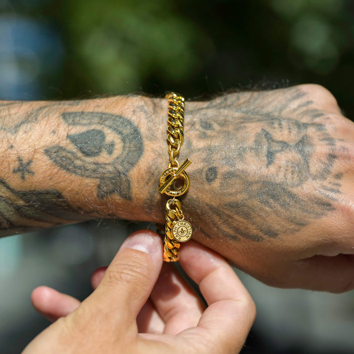 Close-up lifestyle shot of a wrist wearing The Medallion Bracelet - Gold, featuring a bold gold chain with a circular toggle clasp and a small engraved medallion charm, showcasing Ralph Christian’s statement luxury jewelry, Bold by Design.