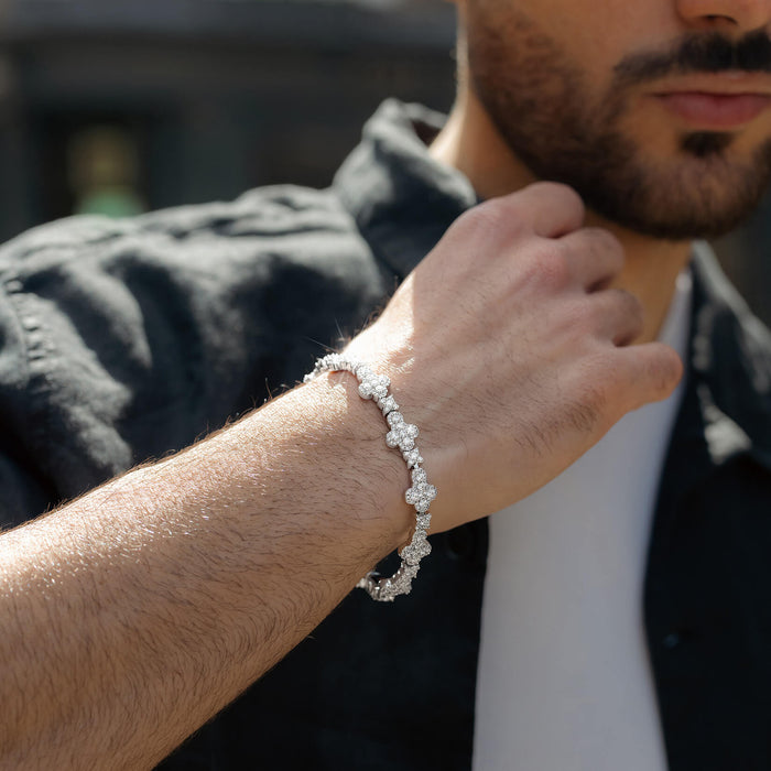 Close-up of a man wearing a bold, silver-toned bracelet with a pattern of sparkling cubic zirconia stones, paired with casual clothing in natural light.