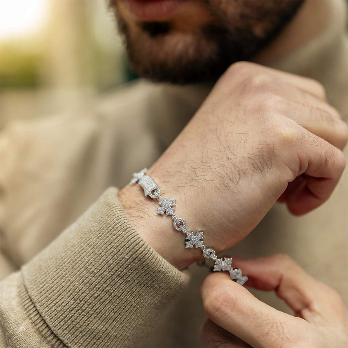 A close-up of a man's wrist wearing The Orion Iced Bracelet, featuring a silver-tone design with cubic zirconia accents, styled with a beige sweater.