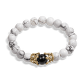 The Royal Howlite Bracelet featuring polished white howlite beads with gray veining, accented by a gold-tone centerpiece clasp holding a black bead, men's luxury jewelry.