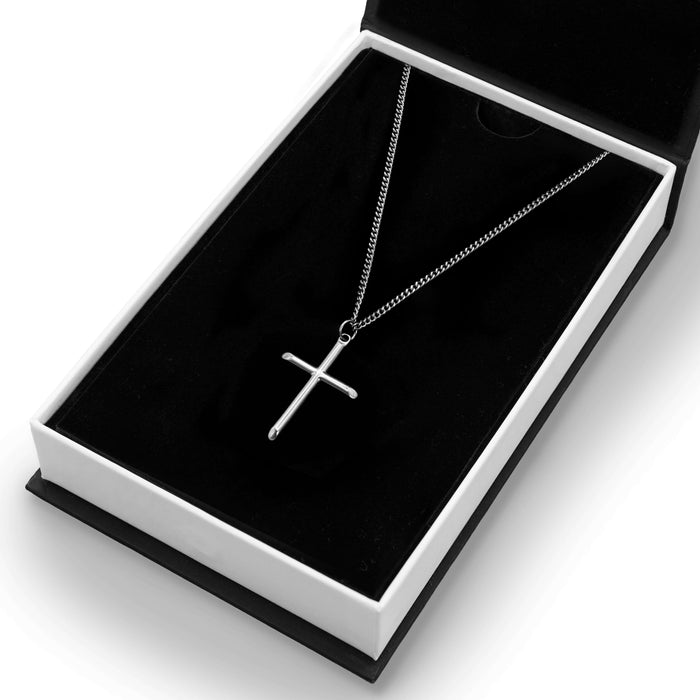 The Silver Cross Pendant - Essentials Collection displayed in a sleek black and white box, featuring a polished silver cross pendant on a matching silver chain for men's jewelry.