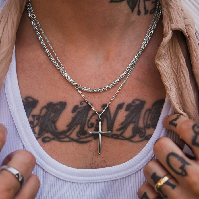 Close-up lifestyle shot of a male model wearing The Silver Cross Pendant - Essentials Collection, paired with layered silver chains, showcasing bold men's jewelry by Ralph Christian.