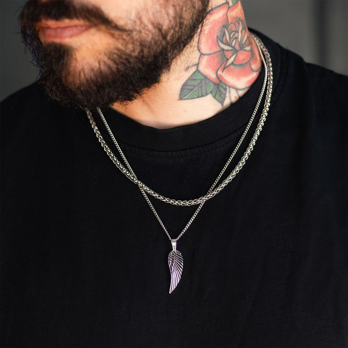 Man wearing a silver chain necklace featuring The Silver Wing Pendant - Essentials Collection, styled with another silver chain and a black shirt, showcasing bold men's jewelry.