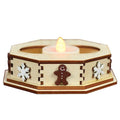 A wooden octagonal candle holder decorated with white snowflakes and a gingerbread man, holding a lit tealight candle.